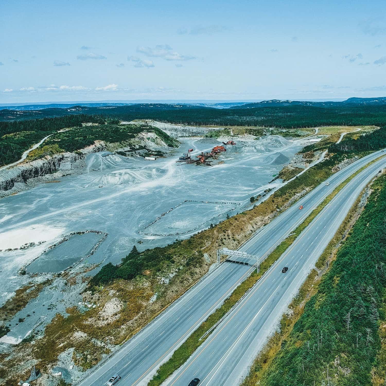 Aerial view of an extraction landscape beside forest and roadway infrastructure.